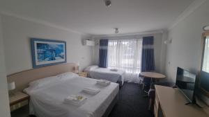 a hotel room with two beds and a television at Forstay Motel in Forster