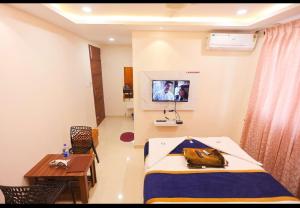 a room with a bed and a table and a tv at S V Grand Inn in Bangalore +8 photos