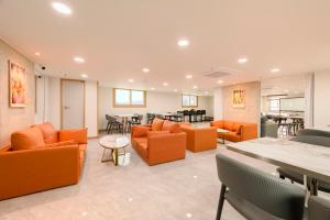 a waiting room with orange chairs and tables at Hotel Moon in Jeju