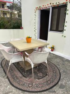 a wooden table and four chairs on a rug at Namya Villas in Bhīm Tāl