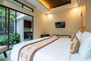 a bedroom with a large bed with a tv on the wall at La Paradis Villa in Canggu