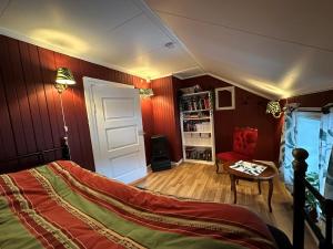 a bedroom with red walls and a bed and a table at Låven Parsellhage in Hoset