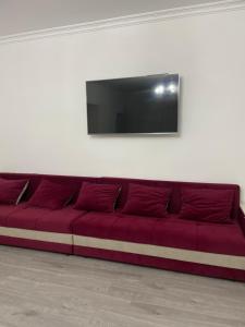 a red couch against a white wall with a flat screen tv at Dos in Kapchagay