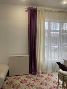 a bedroom with a large window with purple curtains at Dos in Kapchagay