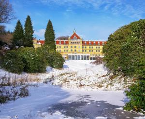 a yellow building with a red roof in the snow at Hotel Vejlefjord in Stouby