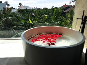 a tub filled with water with red flowers in it at Suom Apartments and Villas Canggu in Canggu