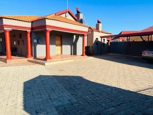 a house with red pillars on a brick driveway at Lovicc Guest house mafikeng in Mahikeng