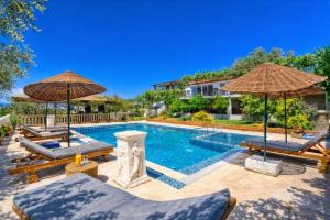 a swimming pool with two chairs and umbrellas at Patara Evleri in Patara