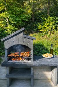 a outdoor grill with chickens and a plate of food at Radovna Chalet with Panoramic View in Mojstrana