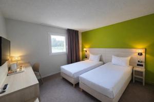 a hotel room with two beds and a green wall at The Originals City, Hôtel Les Bruyères, Dax Nord in Castets