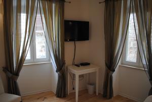 a room with two windows and a tv on the wall at Rooms Piazzetta in Cres