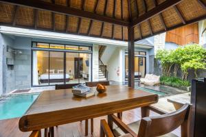 a dining room with a table and a pool at La Paradis Villa in Canggu