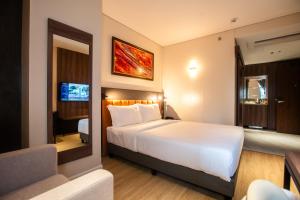 a hotel room with a large white bed and a television at Hotel George in Cebu City +19 photos