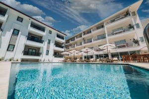 a swimming pool in front of a hotel with umbrellas at The Diplomat Hotel in Turunç