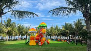 a park with a playground with slides and palm trees at Hải Tiến Resort in Mỹ Ðuc