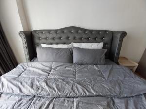 a bed with a gray comforter and pillows at PoolView Condo Near MRT, Nice & Quiet, speedy net in Bangkok +8 photos