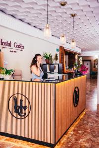 a woman talking on a cell phone behind a counter at Hostal Cortés in Cuenca