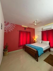 a bedroom with red walls and a bed in a room at Mud apples in Varkala