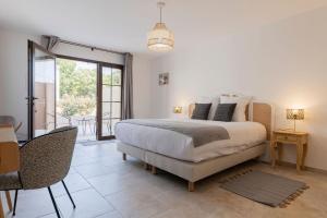 a bedroom with a bed and a table and a balcony at Le Baguier in La Roquebrussanne