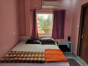a small bedroom with a bed and a window at Tulsi Ganga Hostel in Rishīkesh