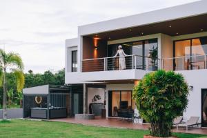 a woman standing on the balcony of a house at Porsampao Luxury Villa in Ban Khok Khilek