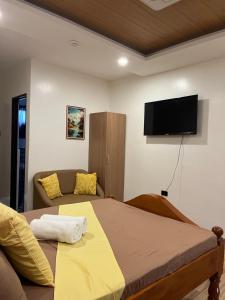 a bedroom with a bed and a couch and a flat screen tv at Escubin Travellers Inn in San Miguel