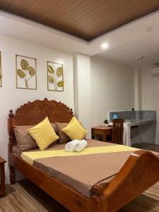 a bedroom with a large wooden bed with yellow pillows at Escubin Travellers Inn in San Miguel