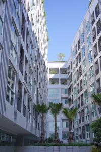 a tall white building with palm trees in front of it at Deco Harmony Pattaya 1 in North Pattaya