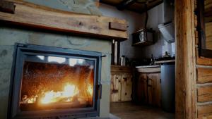 a fireplace in a kitchen with a fire in it at Chatka Pod Dębem in Rozdziele