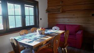 a dining room with a table and a purple couch at Chatka Pod Dębem in Rozdziele +5 photos