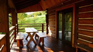 a porch of a log cabin with benches and a table at Chatka Pod Dębem in Rozdziele
