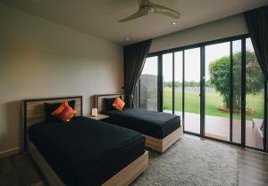 a bedroom with two beds and a large window at Porsampao Luxury Villa in Ban Khok Khilek +33 photos