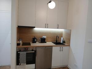 a kitchen with white cabinets and a sink and a stove at Apartman Aurelia in Sremska Mitrovica