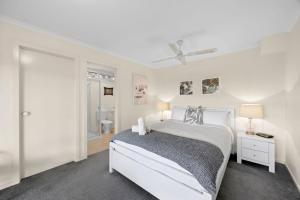 a white bedroom with a white bed and a window at Salty Haven in Moggs Creek