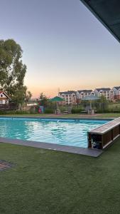 a large swimming pool with green grass and buildings at Elara in Sandton