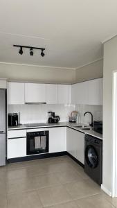 a kitchen with white cabinets and a washer at Elara in Sandton