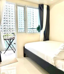 a bedroom with a bed and a large window at Modern Stays Makati Pool View Jazz Residences in Manila