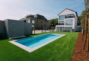 a house with a swimming pool in front of a yard at Luxury Apartment with 4 Rooms, Pool and Modern Comfort in De Haan