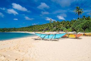 three boats sitting on a beach near the water at Chill Tangalle in Tangalle