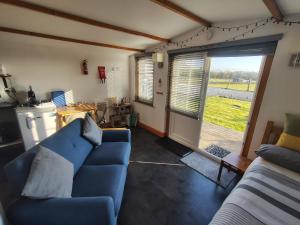 a living room with a blue couch and a sliding glass door at Butterfly Cabin in Millom