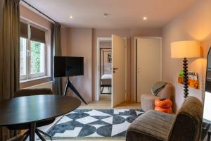 a living room with a table and chairs and a tv at Hotel Riche in Valkenburg