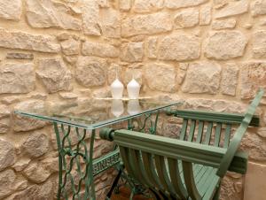 a glass table and a green chair next to a stone wall at Terrazza Campailla in Modica +35 photos