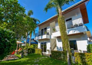 a white building with palm trees in front of it at Phuket Airport Hotel in Nai Yang Beach