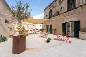 a courtyard with chairs and a tree in front of a building at Terrazza Campailla in Modica