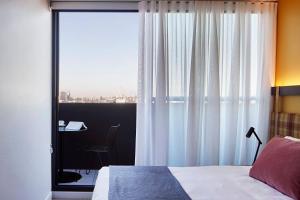 a bedroom with a bed and a desk and a window at Urban Rest Lanbruk in Melbourne +47 photos