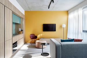 a living room with a couch and a tv on a yellow wall at Urban Rest Lanbruk in Melbourne
