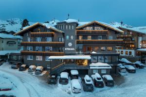 a large building with cars parked in a parking lot at Hotel Kristall in Obertauern