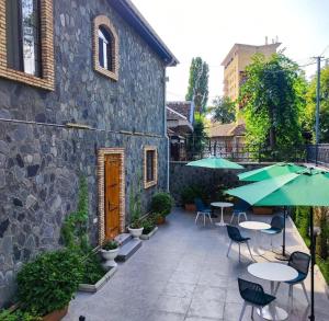 a patio with tables and umbrellas next to a building at Comfort Villa Sheki in Sheki
