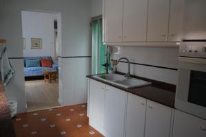 a kitchen with white cabinets and a sink and a living room at Lorea Puerto in Puerto de Sagunto