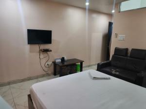 a room with a bed and a chair and a television at Domukha pali ghar in Chepti